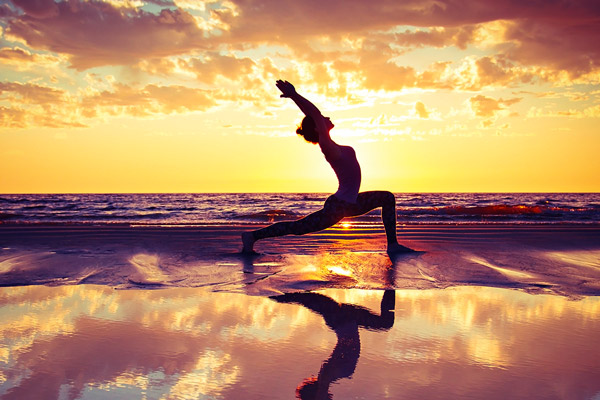 Frau die am Strand Yoga praktiziert