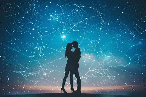 Die Silhouette eines sich umarmenden Paares vor einem funkelnden Sternenhimmel mit sichtbaren Sternbildern. Der Nachthimmel erscheint lebendig durch die verschiedenen Sternbilder, die sich miteinander verbinden. Die Szene strahlt Romantik und Verbundenheit aus, eingebettet in die Unendlichkeit des Universums.